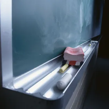 A blackboard with chalk and an eraser resting on the ledge.